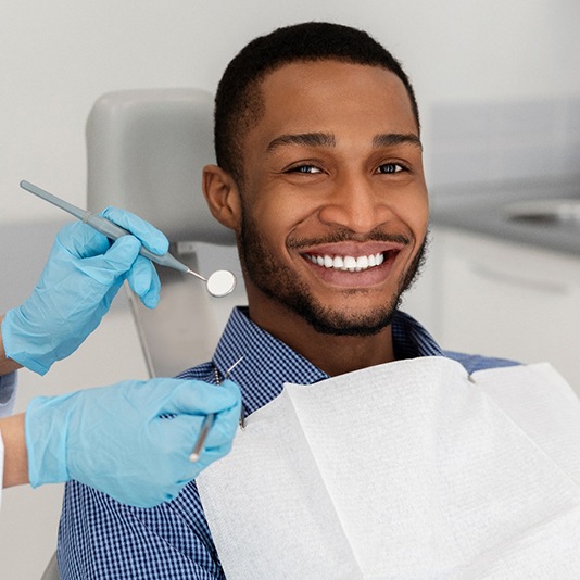Patient smiling in dental chair while dentist examines their teeth