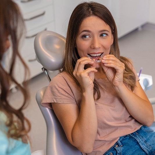 Patient smiling at dentist while holding clear aligner