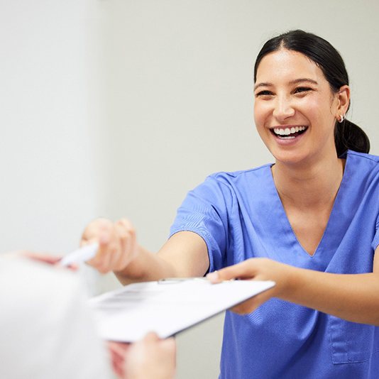 Dental assistant smiling while handing patient form