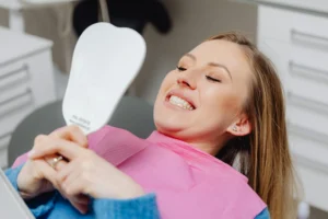 Smiling woman in dentist’s chair looking in a mirror