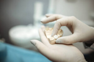 Gloved hands holding a dental crown